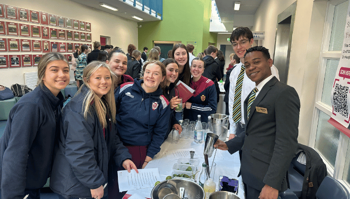 students visiting our campus and smiling as they watch a demonstration of a non alcoholic mojito