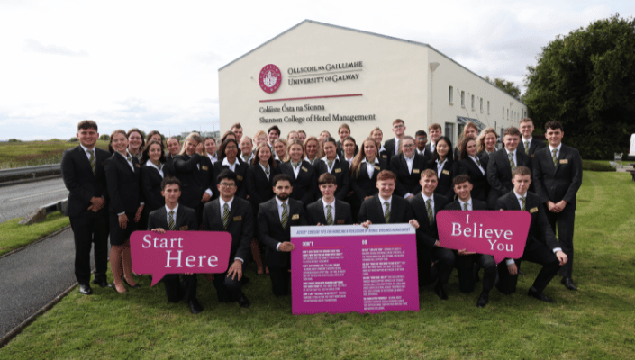 students smiling with start here consent campaign signs